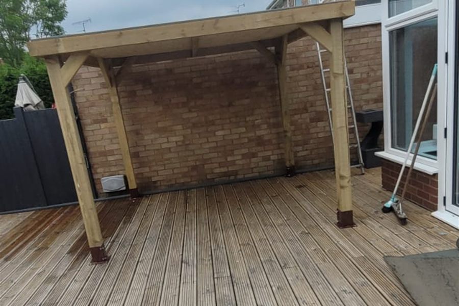 Decking under a timber pergola beside a conservatory