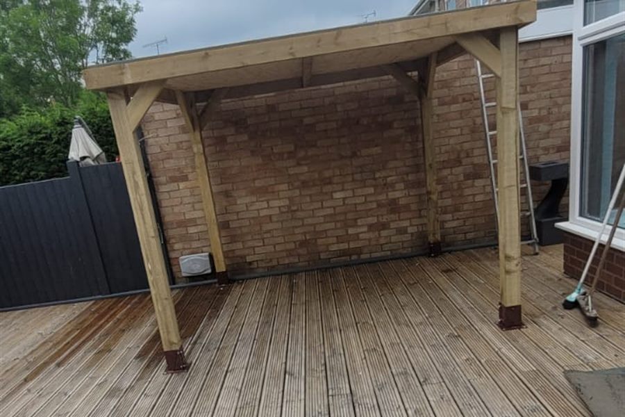 Finished timber decking with a pergola against a brick wall