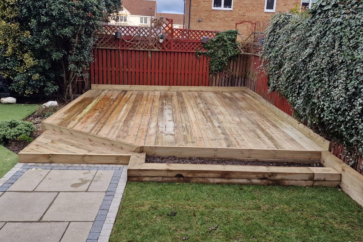Finished decking with a sleeper edge beside a new lawn and slabbed path