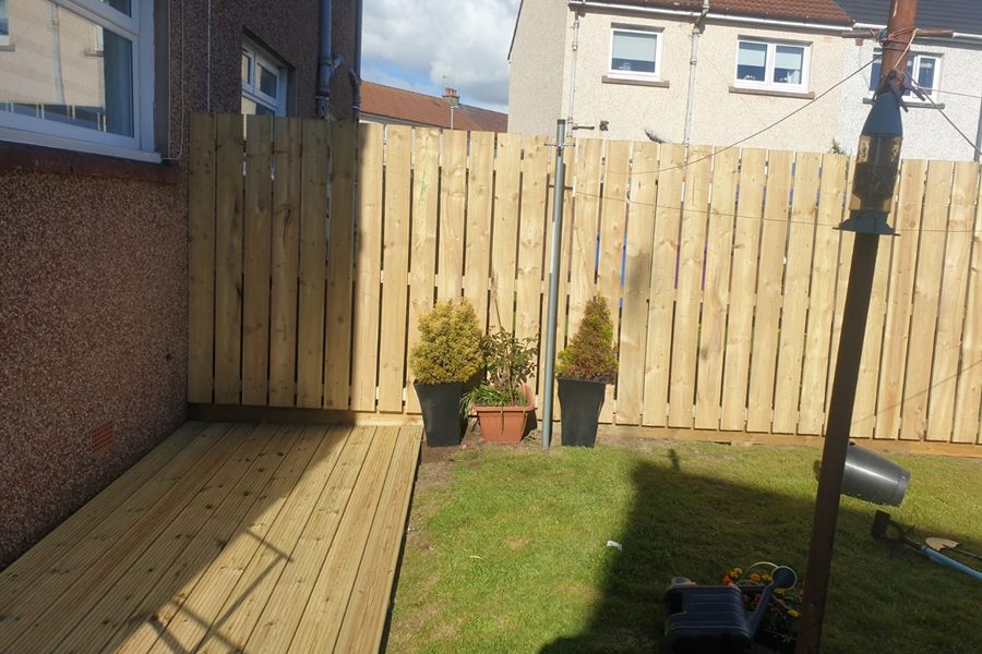Low timber deck along the back of a house with a new fence behind