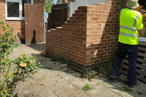 An old brick garden wall being taken down by hand, course by course