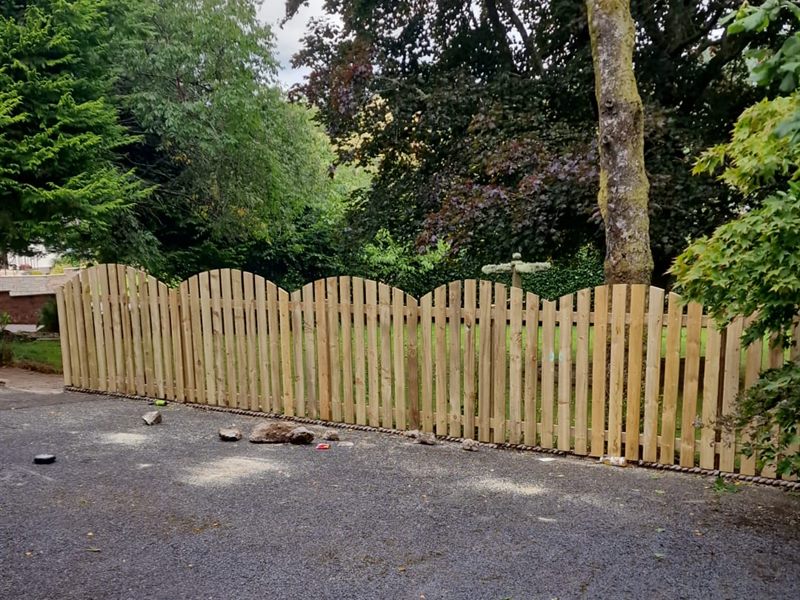 New scalloped picket fence beside a gravel drive