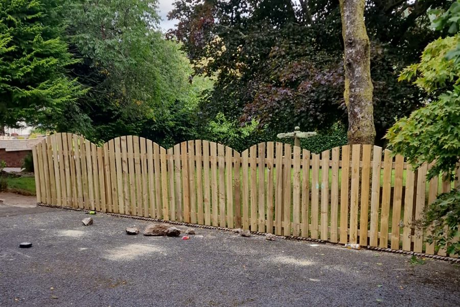 New scalloped picket fence beside a gravel drive
