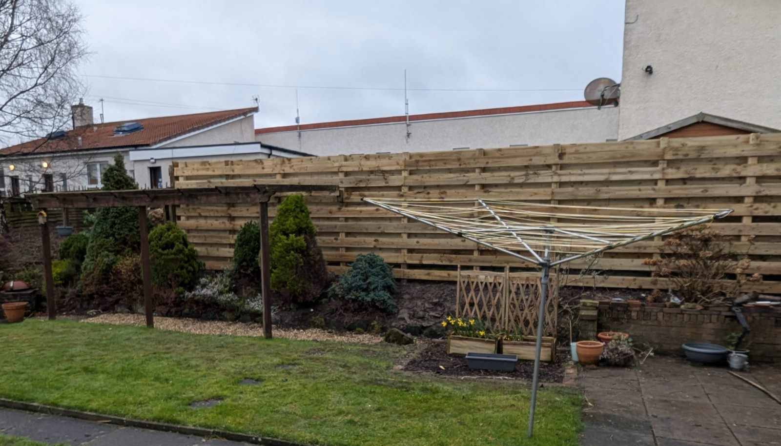 New horizontal slatted fence round a back garden, lawn in front