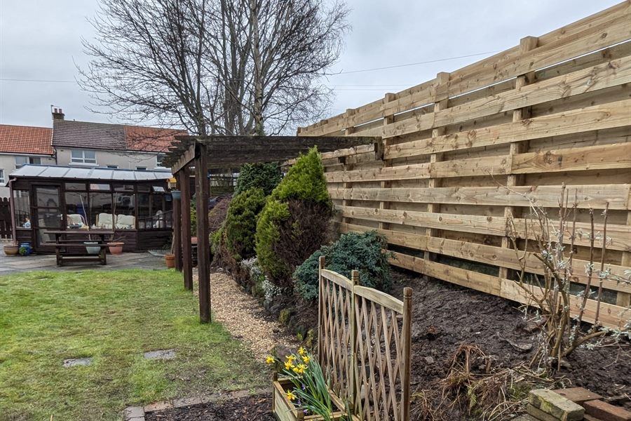 Horizontal slatted fence with a pergola and conifers