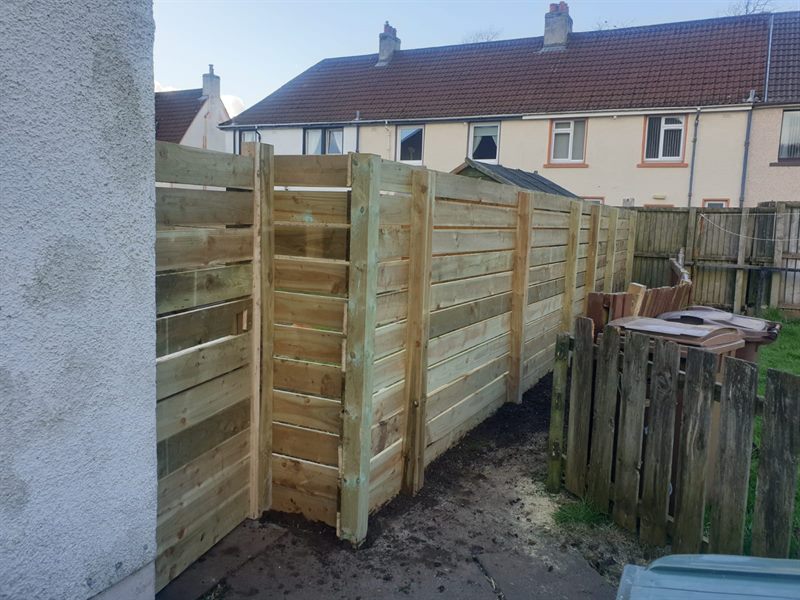 Horizontal slatted fence going up beside the old picket fence