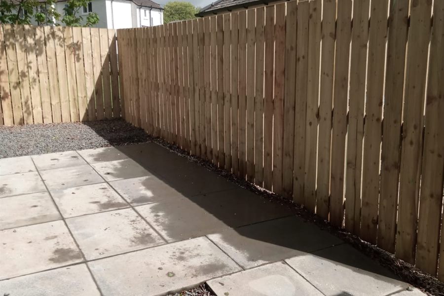 New close-board fence beside a slabbed patio in sunshine