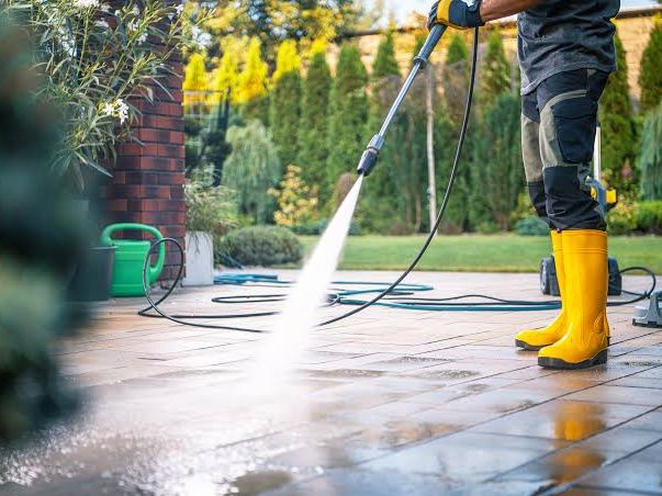 Pressure washing a paved patio, spray lifting the dirt and the slabs running wet