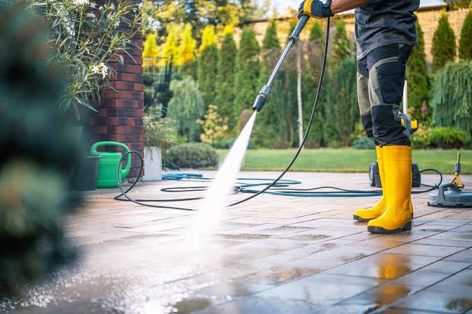 Pressure washing a paved patio, spray lifting the dirt and the slabs running wet