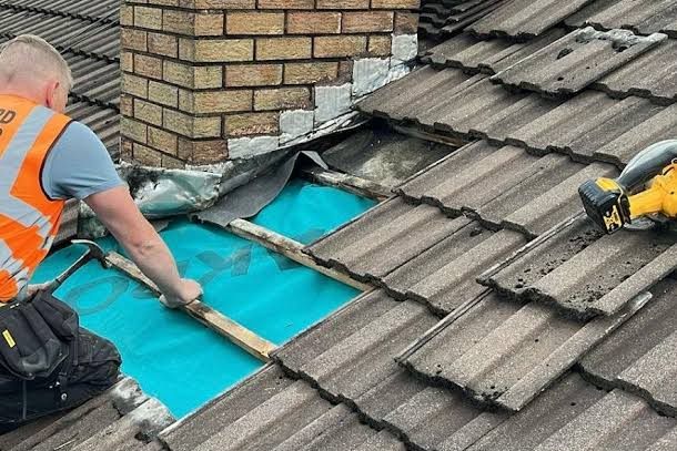 Tiles lifted beside a chimney with the membrane exposed, ready for the repair