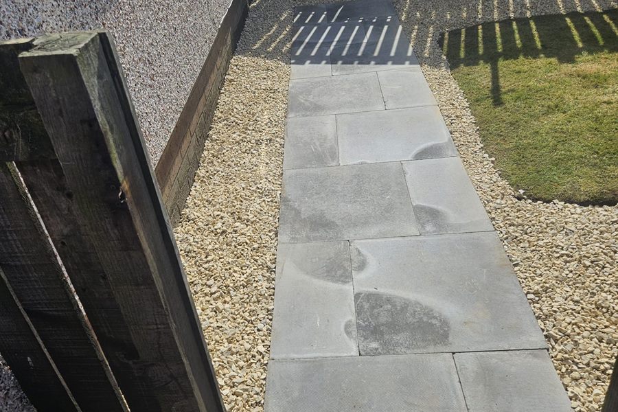 Slab path beside a house with gravel one side and lawn the other