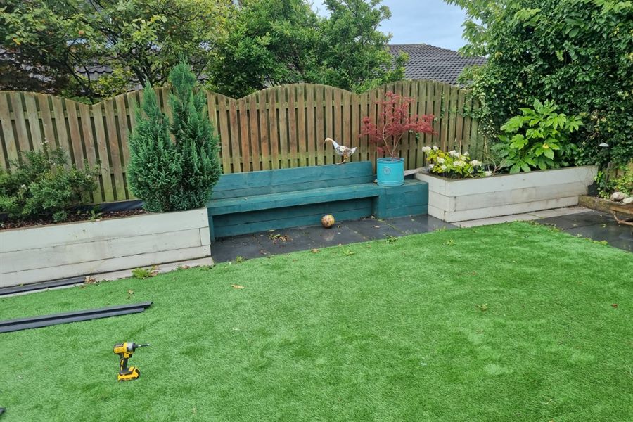 Artificial lawn with sleeper planters and a painted bench