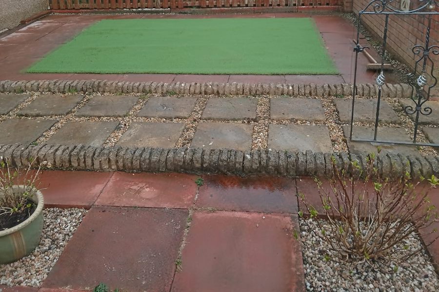 Artificial lawn square in a small front garden with slab and gravel edging