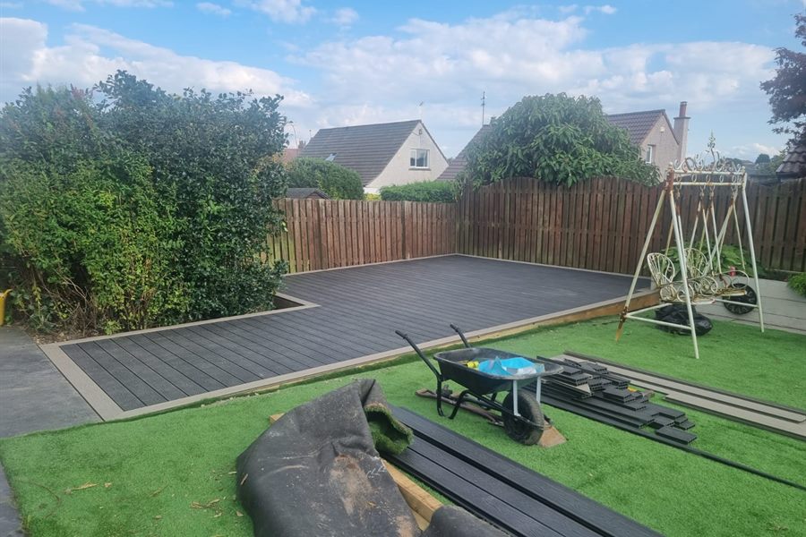 Artificial lawn and composite decking going in with a swing seat behind