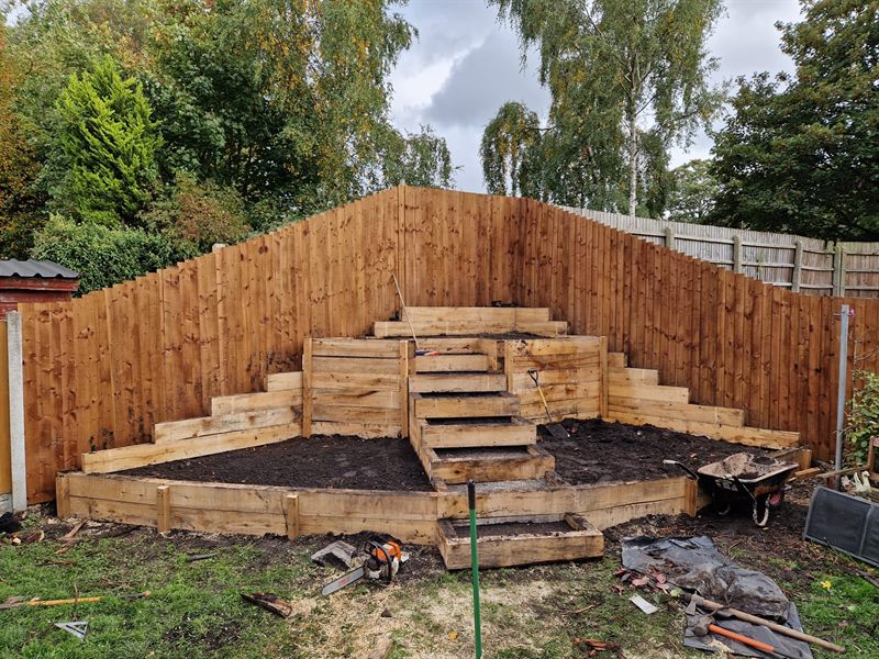 Tiered sleeper retaining beds being built against a new fence