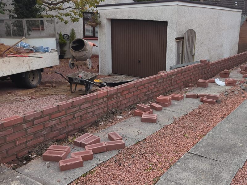 New brick garden wall going up along a drive with a mixer on site